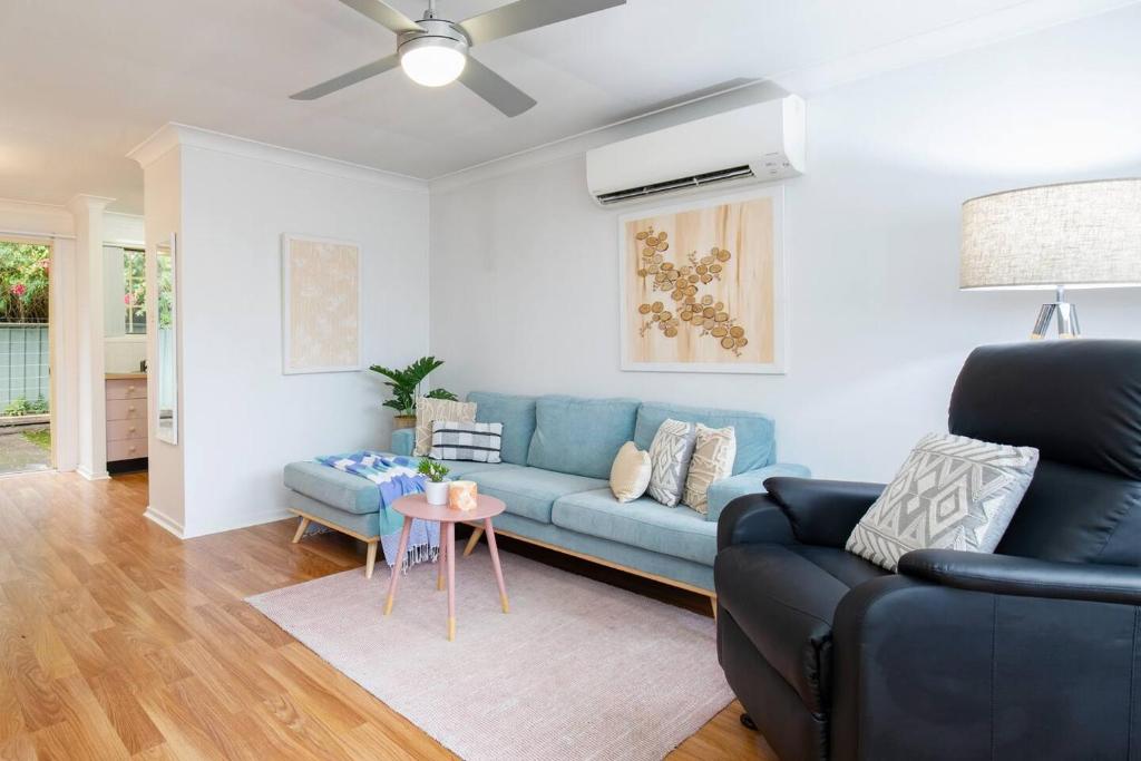 a living room with a blue couch and a table at Tighes Hill Hideaway - Alfresco Living by the Park in Newcastle