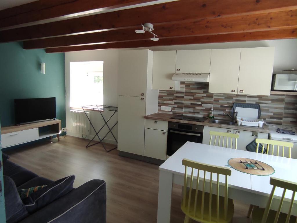 a kitchen with a white table and a kitchen with a counter at Le gîte de ty stumo1 in Neulliac