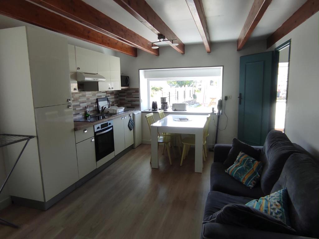 a kitchen and living room with a couch and a table at Le gîte de ty stumo1 in Neulliac