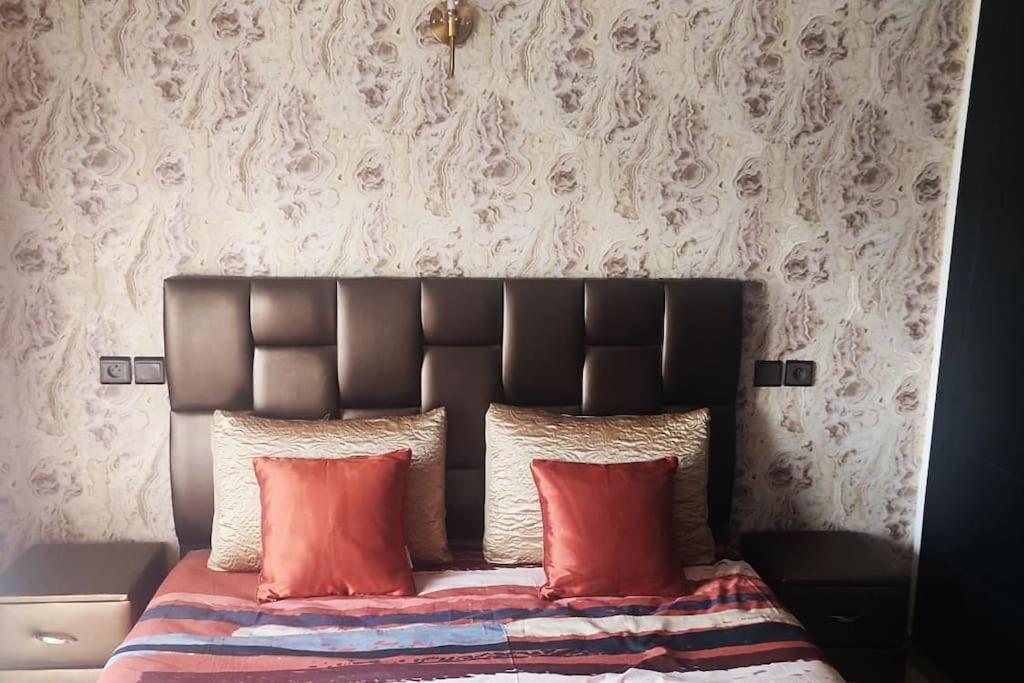 a bed with a black headboard and red pillows at Chez Noufissa in Marrakesh