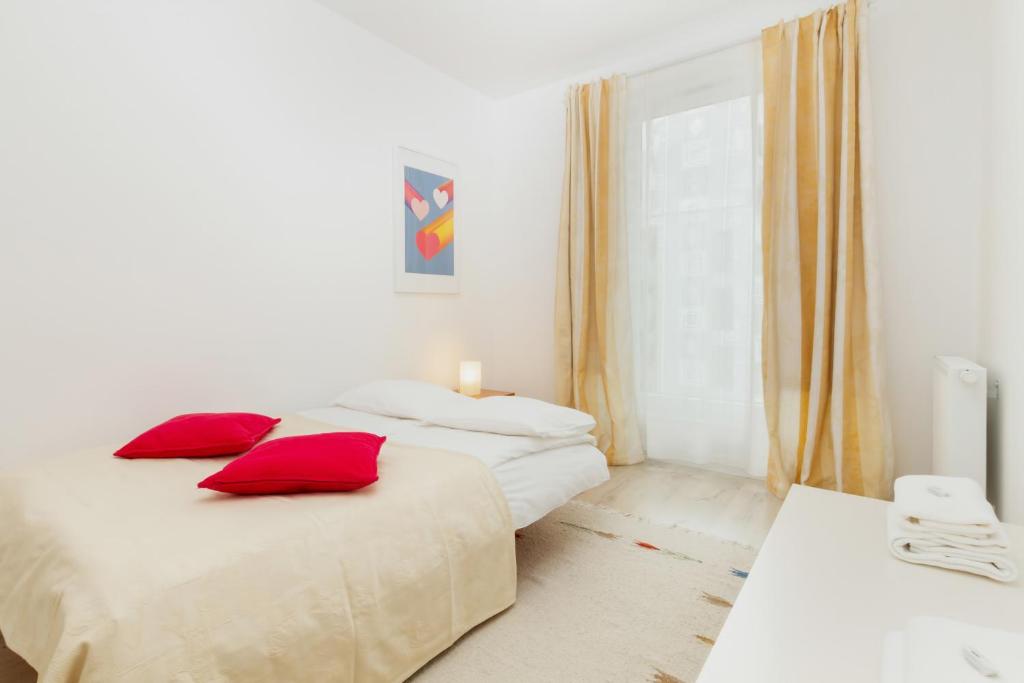 two beds in a white room with red pillows at Apartment Harmonia Oliwska by Renters in Gdańsk