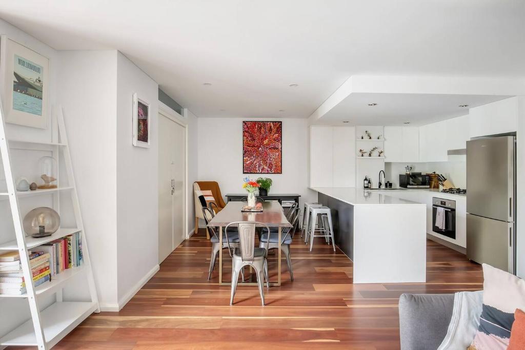 a kitchen and dining room with white walls and wooden floors at Harbourside at Woolloomooloo with Balcony Views in Sydney