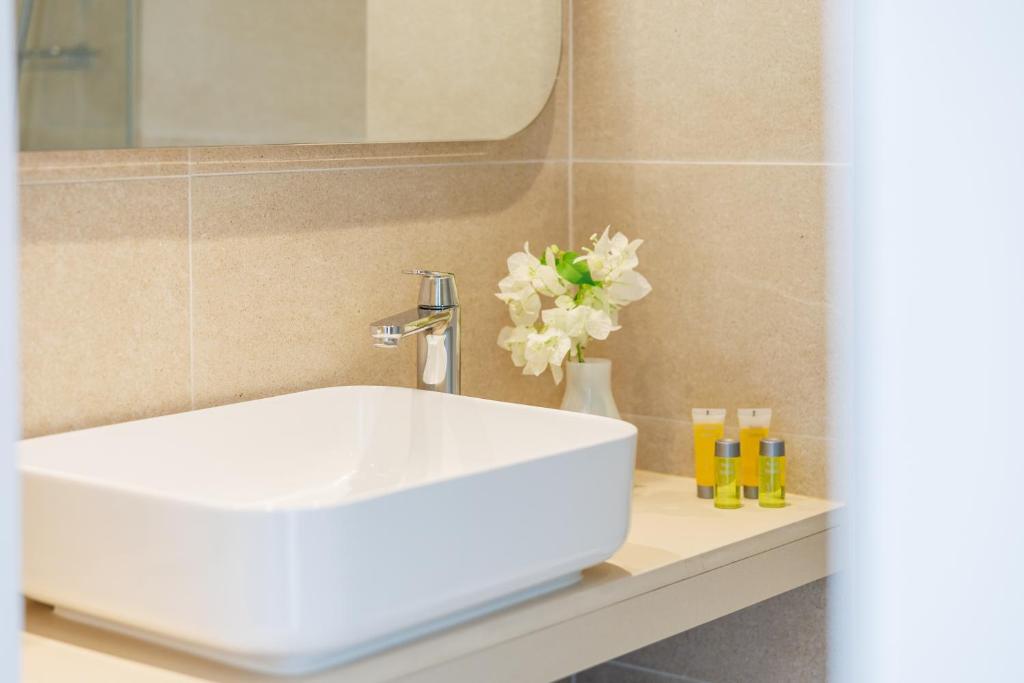 a bathroom with a white sink and a vase with flowers at Nissi Park Hotel in Ayia Napa