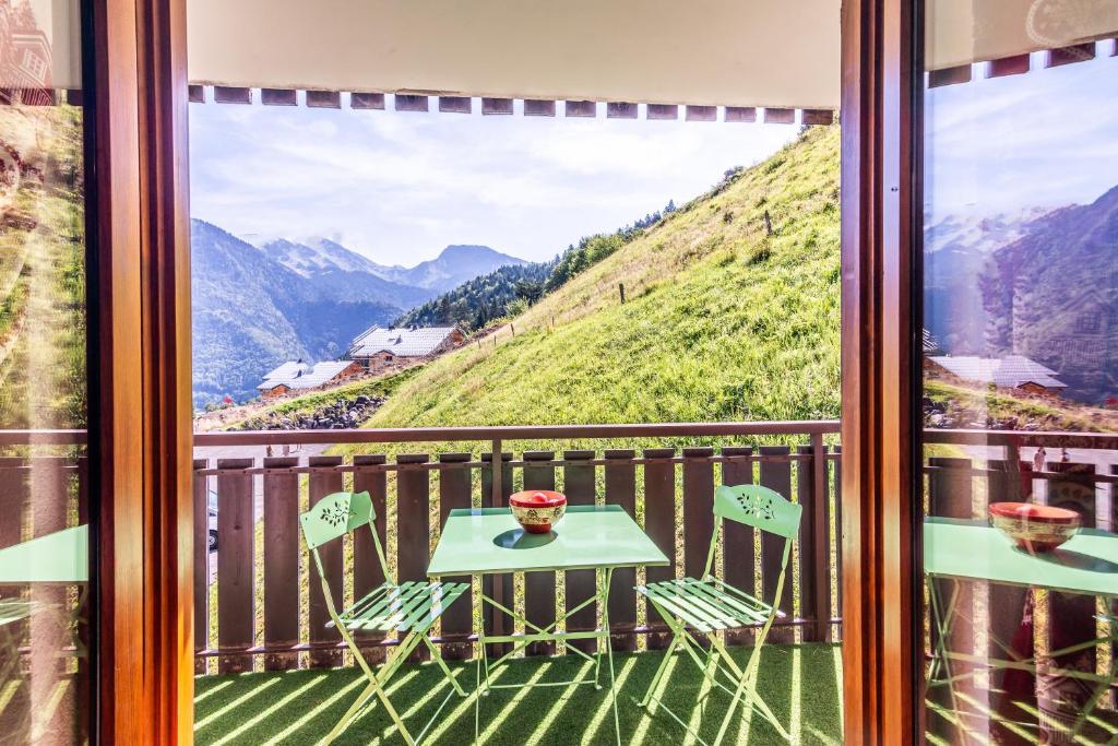 a table and chairs on a balcony with a view of mountains at Le Petit Aulps - Studio avec vue montagne in Saint-Jean-d'Aulps