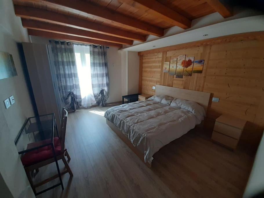 um quarto com uma cama grande e uma parede de madeira em Tranquillità e Relax em Villeneuve