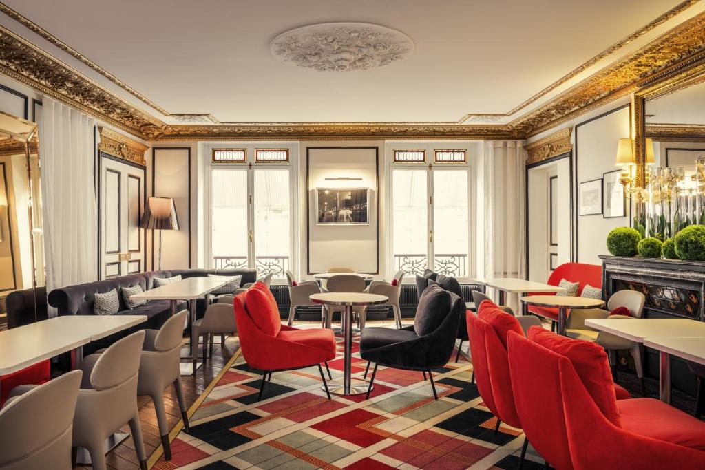 un restaurant avec des tables, des chaises et des chaises rouges dans l'établissement Mercure Paris Opera Louvre, à Paris