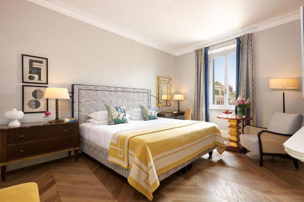 a bedroom with a bed and a chair and a window at Rocco Forte Hotel De Russie in Rome
