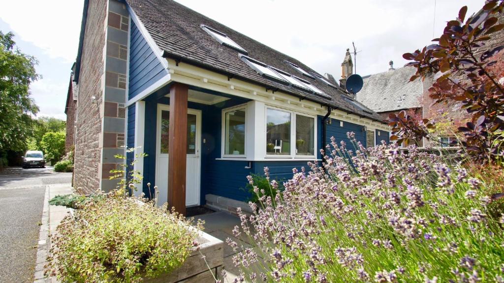 a blue house with flowers in front of it at Fire Station Cottage in Comrie