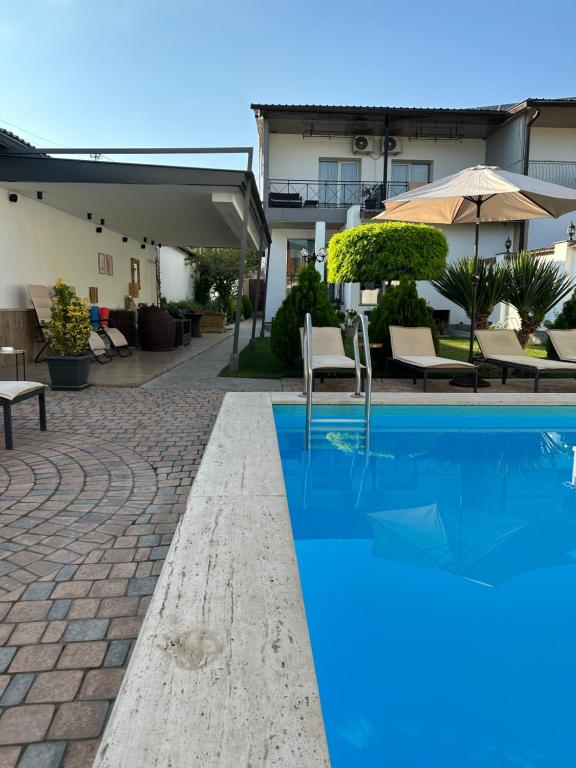 ein Pool in einem Hotel mit Stühlen und einem Sonnenschirm in der Unterkunft Garden Lounge Hotel in Yerevan