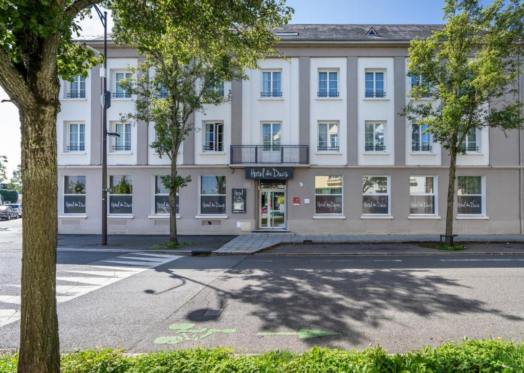 un gran edificio blanco con árboles delante de él en Hotel des Ducs, en Alençon