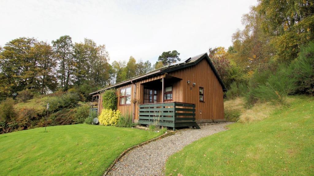 mały drewniany dom na wzgórzu z ogródkiem w obiekcie Morenish Mews Kenmore Cottage w mieście Morenish