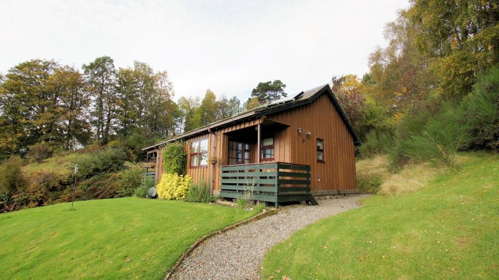 een klein houten huis op een heuvel met een tuin bij Morenish Mews Kenmore Cottage in Morenish