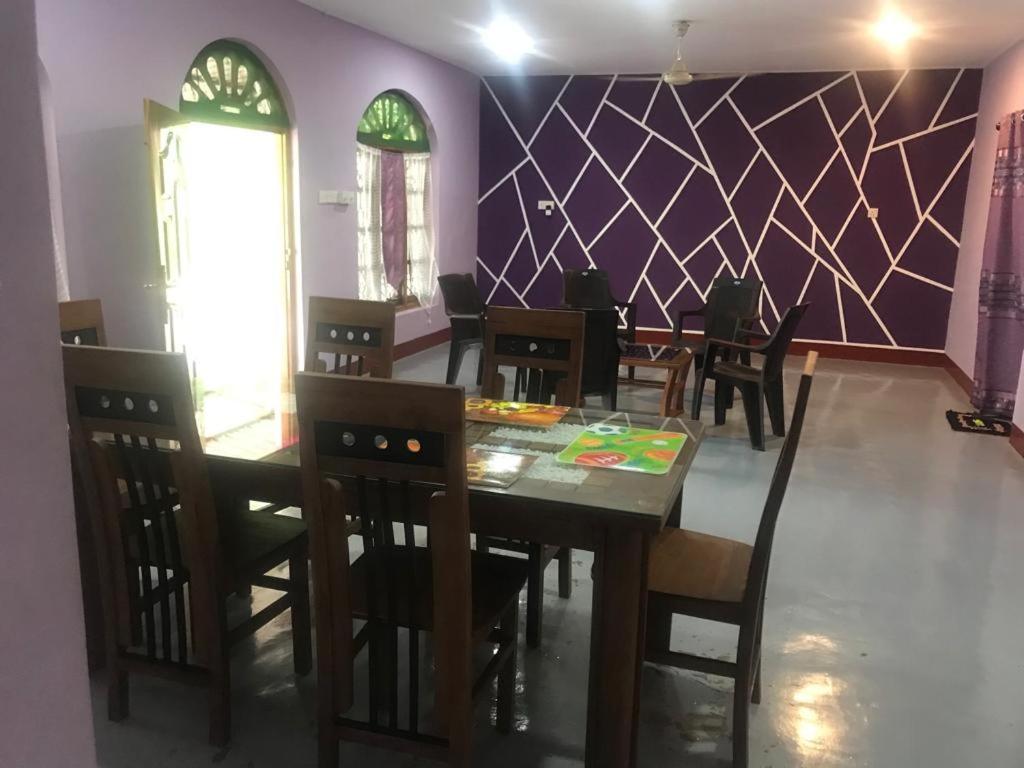 a dining room with a table and chairs and purple wall at MSV VILLA RÉSIDENCE HOME in Batticaloa