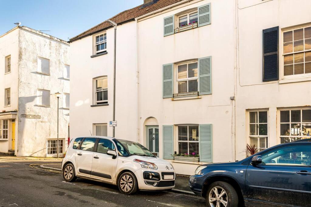 two cars parked on a street in front of buildings at Beautiful little Townhouse situated in Brighton's Regency Conservation Area in Brighton & Hove