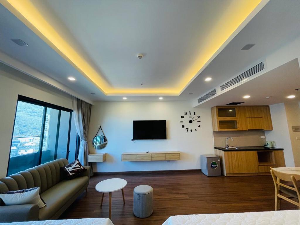 ein Wohnzimmer mit einem Sofa und einem TV an der Wand in der Unterkunft FLC Apartment Beach Quy Nhơn in Quy Nhon