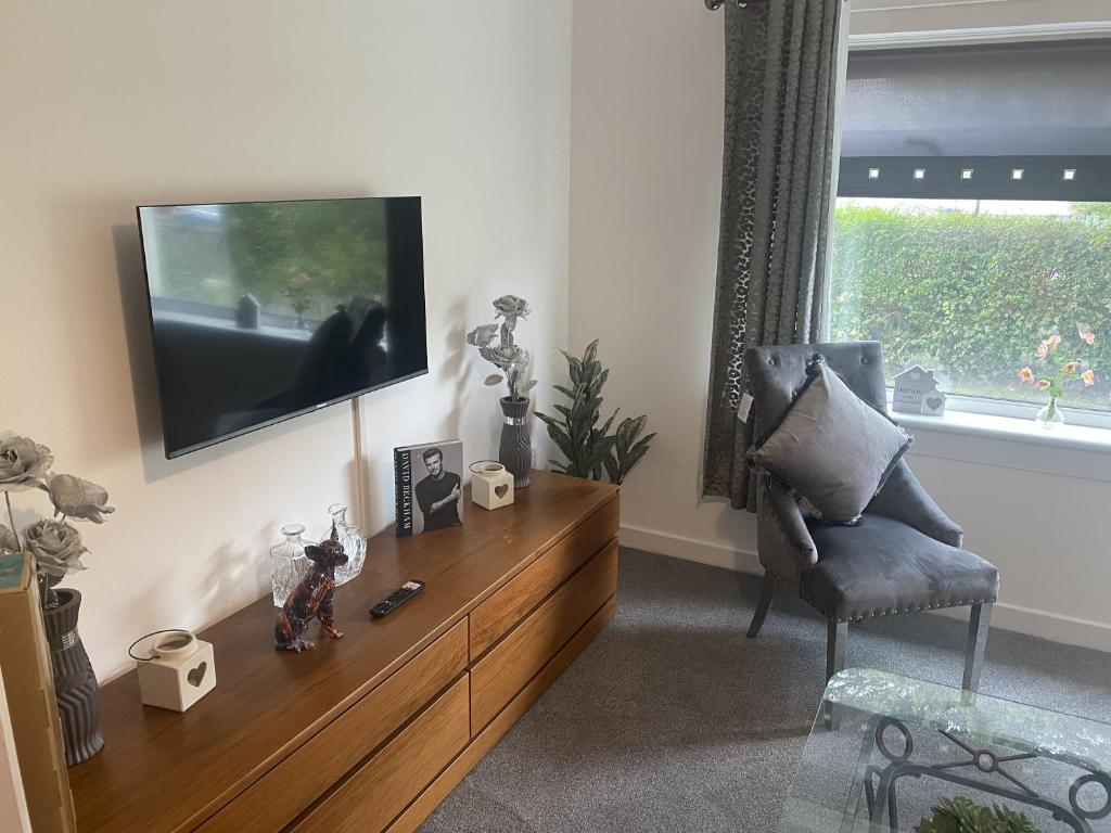a living room with a tv and a chair at Clavens House in Glasgow