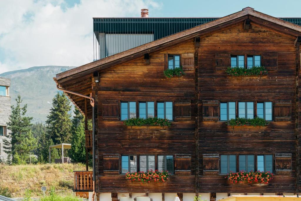 a wooden house with windows and flowers on it at Casa Mulania in Laax