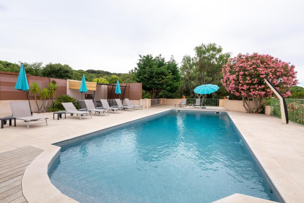una piscina con sillas y sombrillas en un patio en Chambres d'Hotes Les Amandiers, en Saint-Tropez