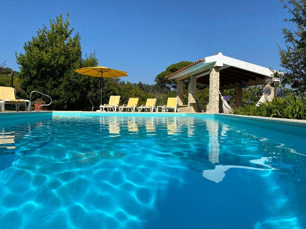 una piscina con sombrilla y sillas en Countryside & Beach House Ericeira - Pêra Miúda, en Ericeira