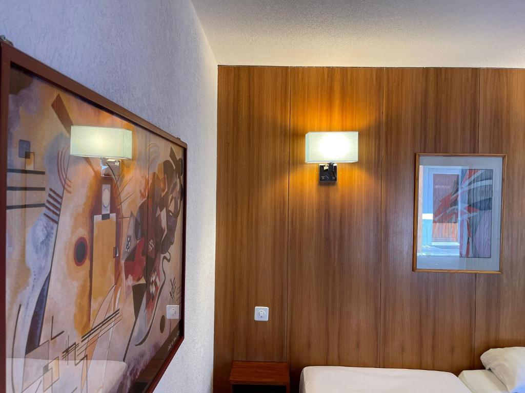 馬蒂尼威爾的住宿－Motel des Sports Martigny，一间卧室配有两盏灯,墙上挂着一幅画