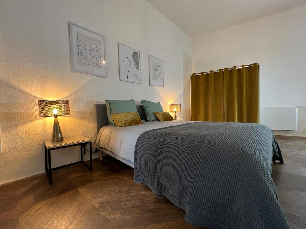 a bedroom with a bed and a table with a lamp at Nature & Médiéval, gîte de charme 4 étoiles in Largentière