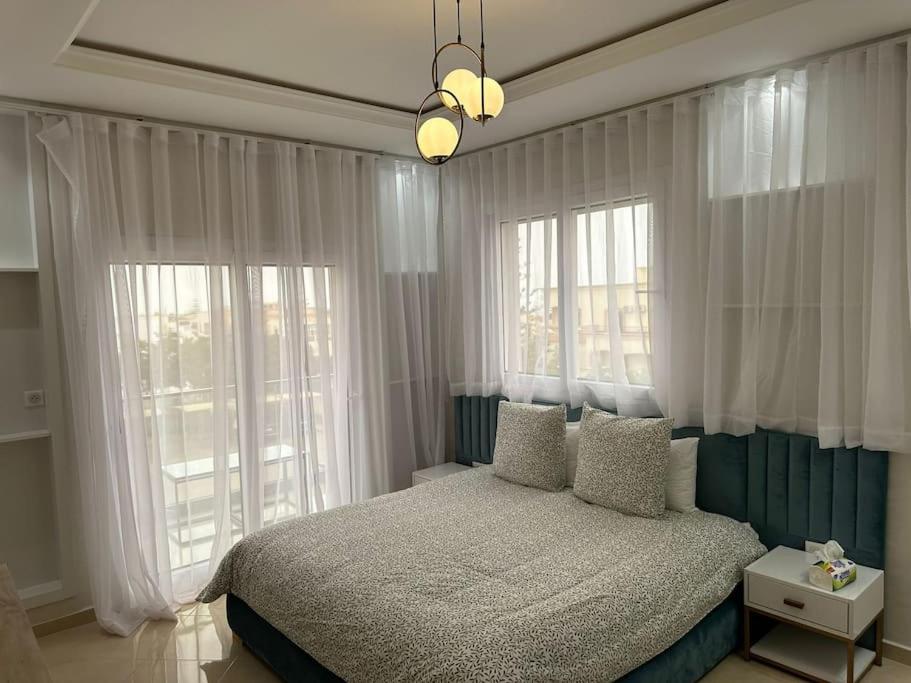 a bedroom with a bed and two large windows at Spacieuse villa familiale avec piscine Founty in Agadir