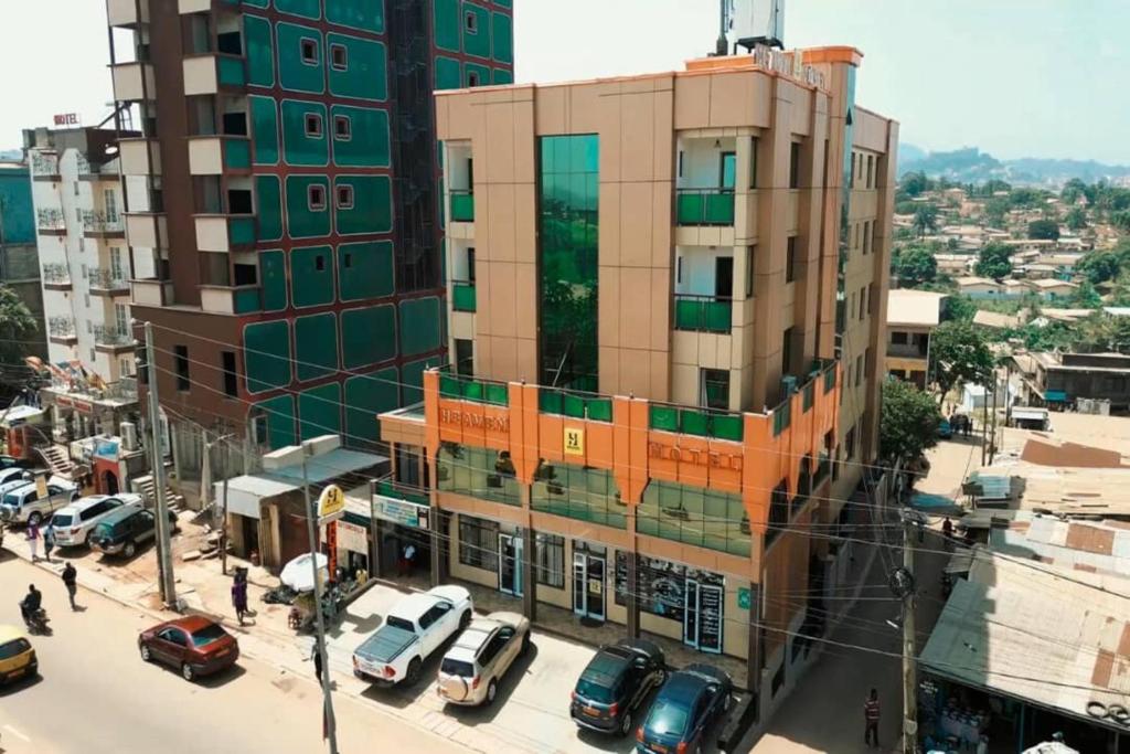 een stadsstraat met auto's die voor een gebouw geparkeerd staan bij New Heaven Hôtel in Yaoundé