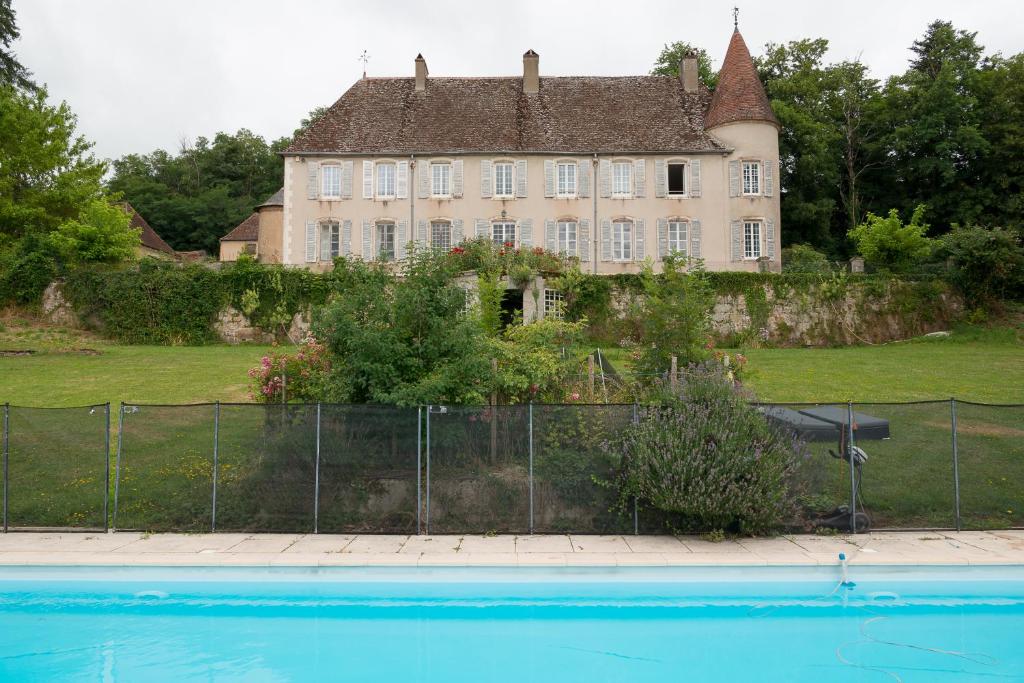 une vieille maison avec une piscine en face de celle-ci dans l'établissement Château pour se retrouver, à Larochemillay