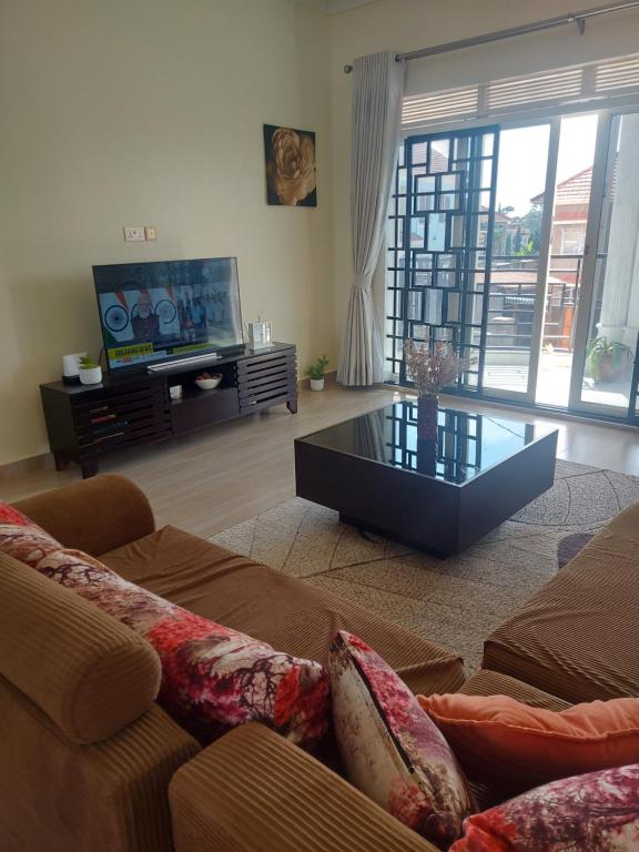 een woonkamer met een bank en een tv bij Freeve Suites Akright City Bwebajja in Buzzi