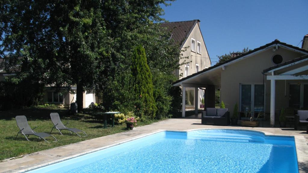 einen Pool in einem Garten mit zwei Stühlen und einem Haus in der Unterkunft Les Jardins du Golf in Metz