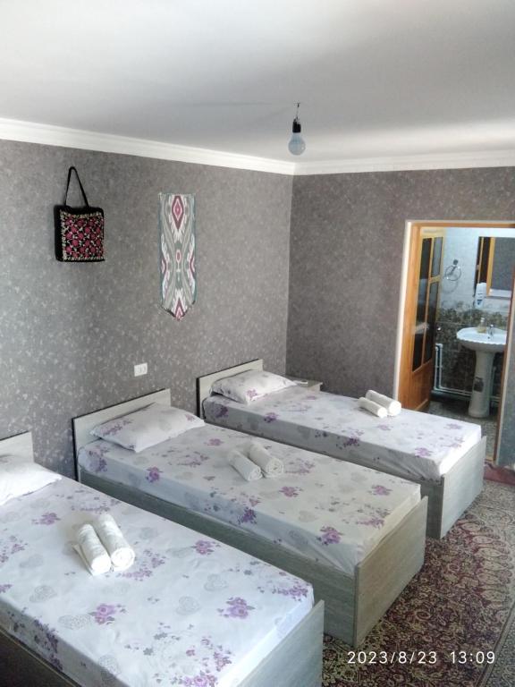 a room with three beds in it at Nur-Niso Guest House in Bukhara