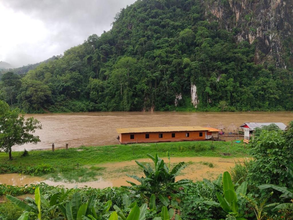 a building in the middle of a river with a mountain at My Nongkhiaw in Nongkhiaw