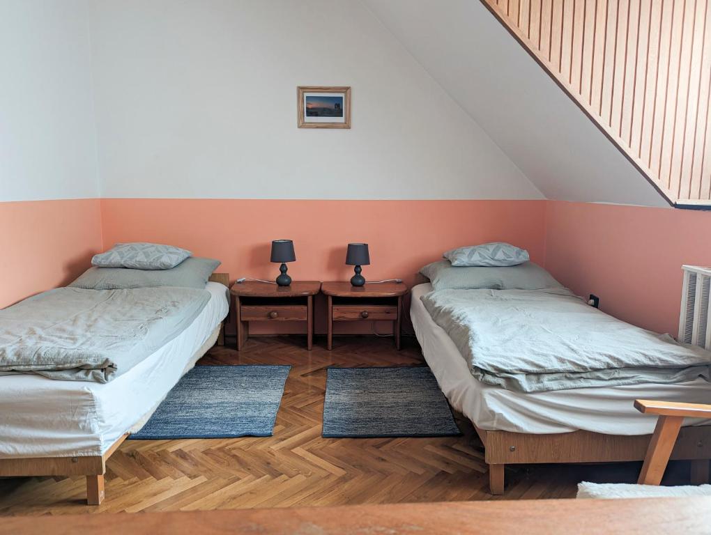 2 Einzelbetten in einem Zimmer mit 2 Tischen in der Unterkunft Várkapitány-lak in Csesznek