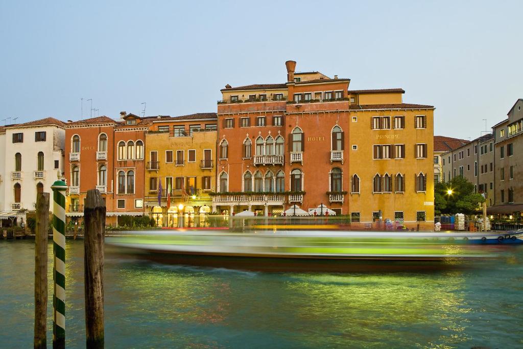 a boat traveling down a river in front of buildings at Hotel Principe in Venice