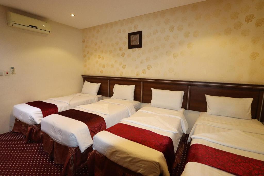 a row of four beds in a room at Ayan ALMUEABADH -1700m to ALharam in Mecca