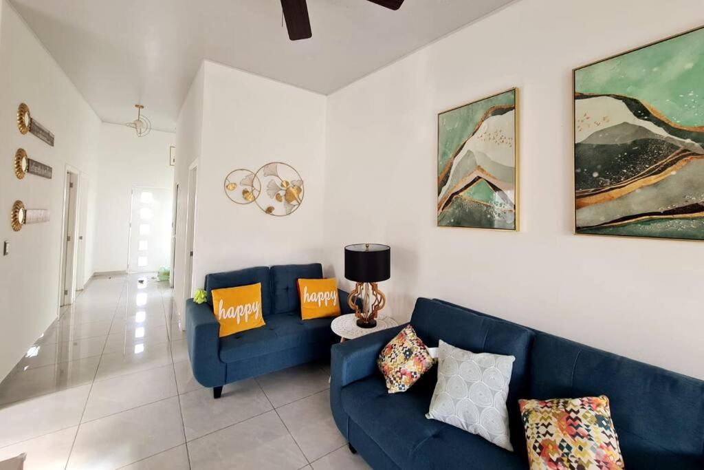 sala de estar con sofá azul y pinturas en la pared en Casa familiar en San Miguel