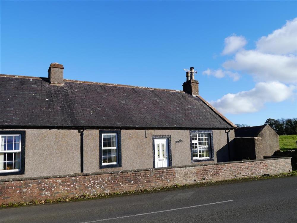 an old brick house on the side of a road at Branta Cottage in Dumfries