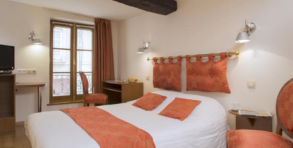 um quarto de hotel com uma cama com almofadas laranja em Le Saint Michel em Sedan