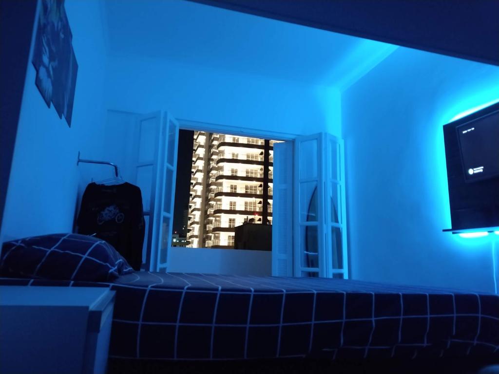 Dieses blaue Zimmer verfügt über ein Fenster mit Blick auf ein Gebäude. in der Unterkunft Apartamento Top Vista mar Boqueirao Gonzaga in Santos