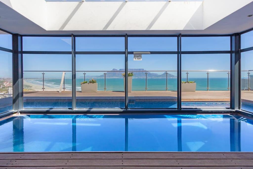 a swimming pool with a view of the ocean at Modern 3 Bed Apartment Blouberg in Cape Town