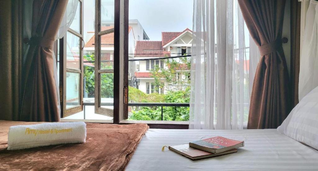 a bed with two books on it with a large window at Amy 2 Hostel Hue in Hue