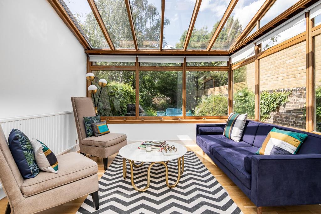 einen Wintergarten mit einem lila Sofa und einer Glasdecke in der Unterkunft 4 BR Edwardian family house wgarden, Notting Hill in London