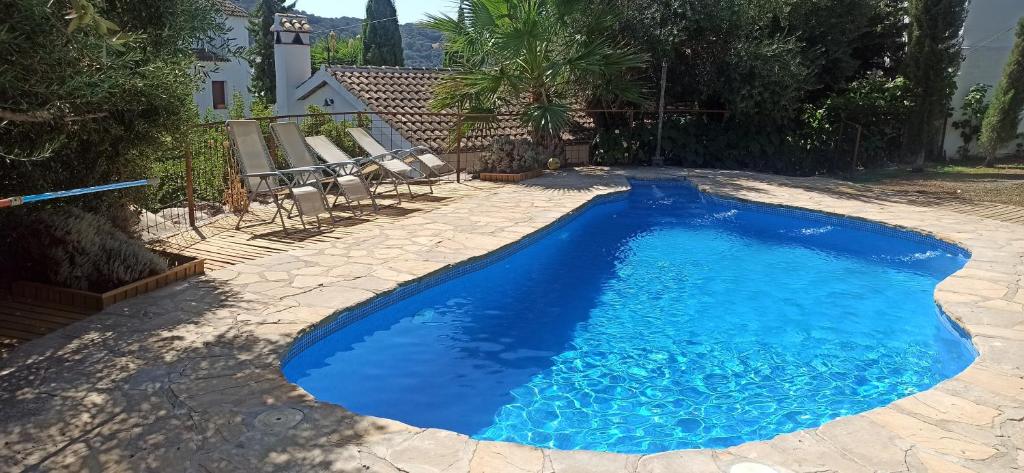 een zwembad met blauw water in een tuin bij Casas de Almajar in Prado del Rey