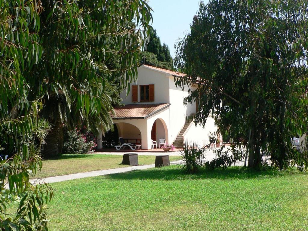 uma casa branca com um banco na relva em A semi detached bungalow with AC near the coast of Tuscany em La Caduta