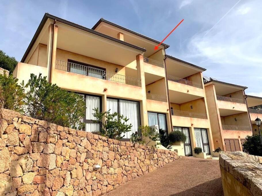 un edificio con una pared de piedra delante de él en Casa Smeralda - Piscina e vista sul Mare!, en Trinità dʼAgultu