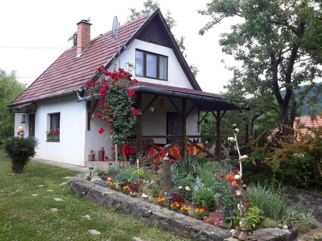 una casa blanca con flores en el patio delantero en Szarvaskő Szérűskert vendégház, en Szarvaskő