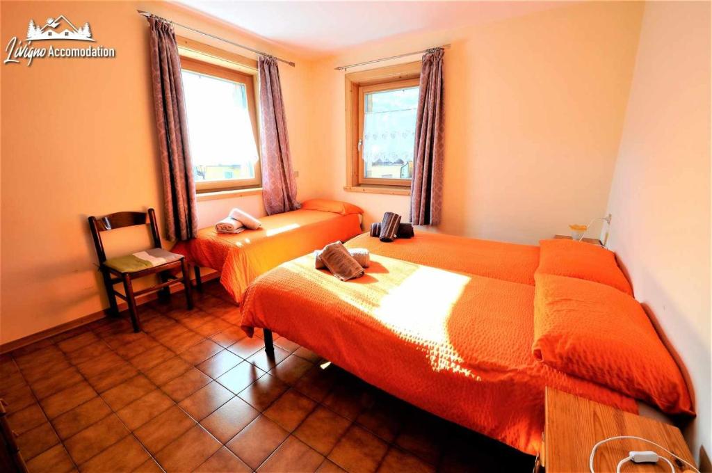 1 dormitorio con 2 camas, silla y ventana en Appartamenti Barin, en Livigno