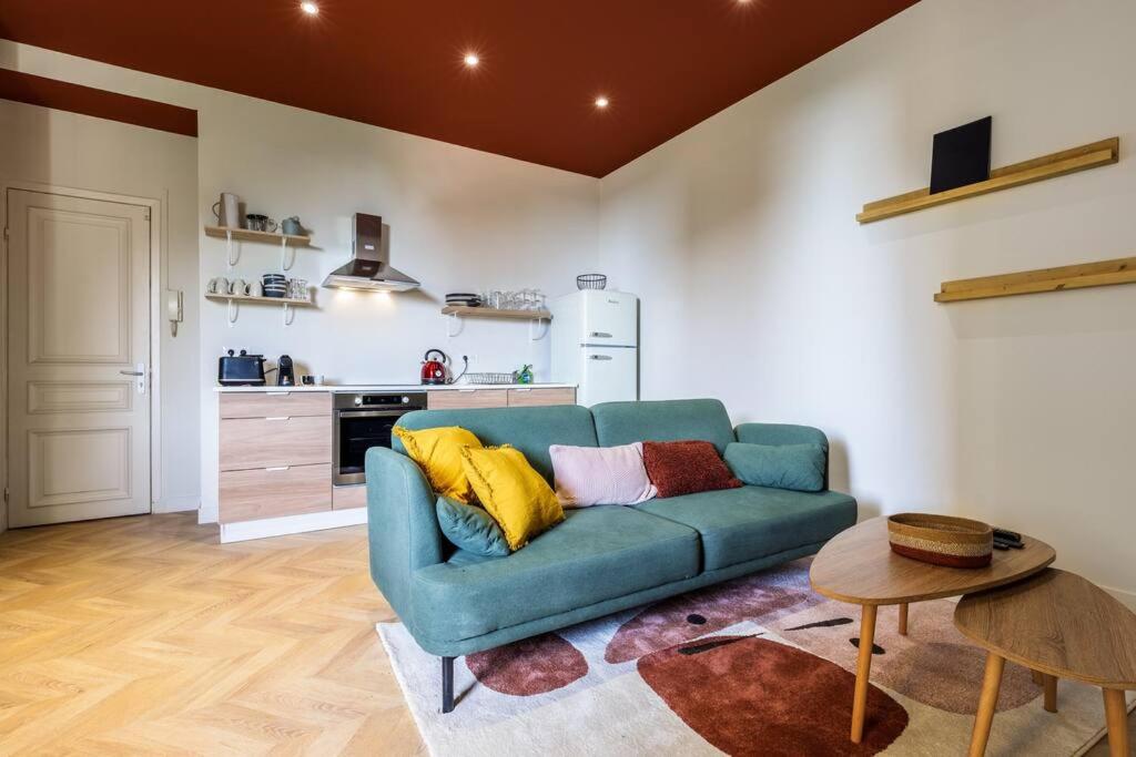 a living room with a blue couch and a kitchen at Charmant 3 pièces vue mer in Villefranche-sur-Mer