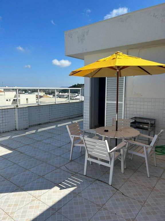 a table and chairs with a yellow umbrella on a roof at Cobertura de 3 Quartos Duplex in Cabo Frio