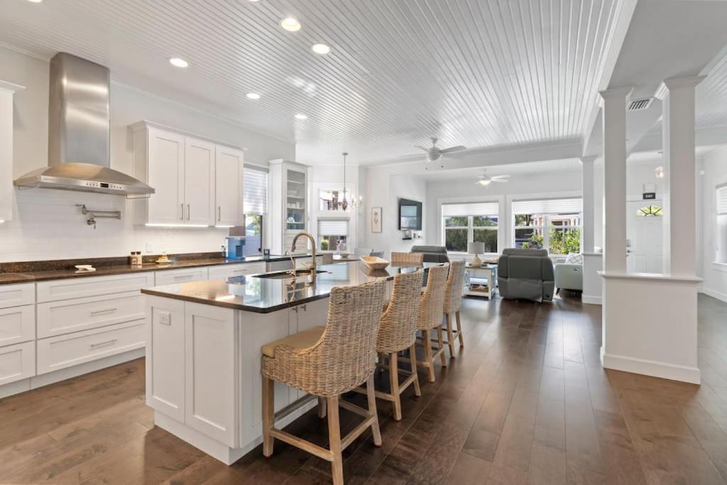 a kitchen with white cabinets and a bar with chairs at Cobalt Cottage History at your doorstep in Saint Augustine